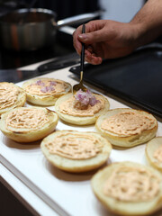 chef preparing hamburger bun with sauce and ingredients to make hamburgers
