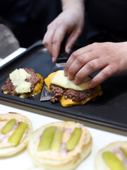 chef preparing a meat burger with melted cheese