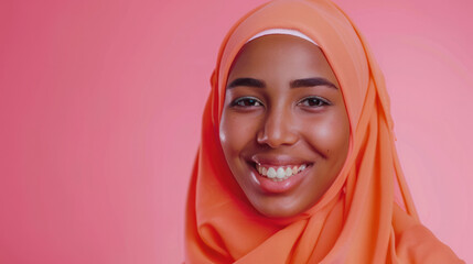 A positive Muslim woman wearing a traditional headscarf smiles happily at the camera