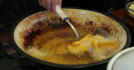 Mandioca frita inside large frying boiling pan with oil