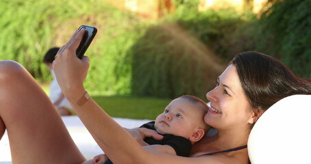 Mom and baby taking selfie together outside by the pool