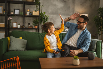 Father and son play video games on a mobile phone and enjoy at home