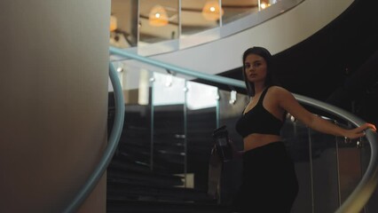 Attractive, athletic girl, model, woman goes down the stairs of a luxury, elite sports complex and smiles, vip, health and care, member of society, sports club, fitness clothing, lifestyle, real time