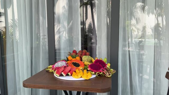 Fresh fruit plate and set of summer fashionable beach accessories, top view Tropical beach lifestyle.Plate . fruit on the hotel porch 