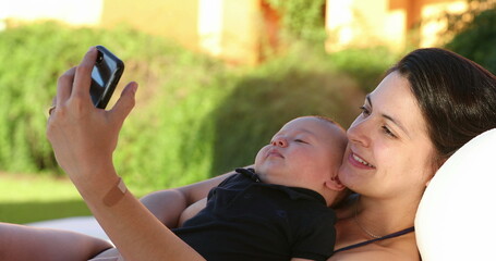 Mother taking selfie with her baby posing for photo outdoors