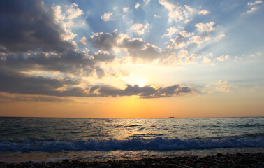 A beautiful sunset over the sea with orange clouds, and a calm tide