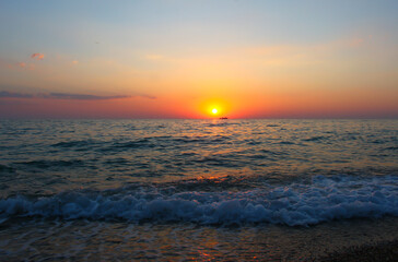 A beautiful sunset over the sea with orange clouds, and a calm tide