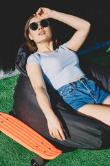 Young hipster girl in sunglasses sitting for little rest after spending time on city with...