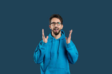 A man wearing a blue hoodie is seen gesturing with his hand in this photograph. The gesture appears...