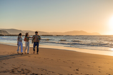 copyspace Three hispanic friends enjoy a leisurely stroll at sunset on the beach