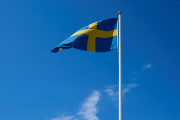 Swedish flag on blue sky. Swedish flag fluttering on wind. National Day of Sweden. Swedish Flag Day.  
