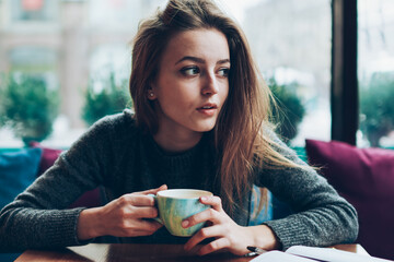 Attractive female author thoughtful looking away in break of creating new article indoors,...