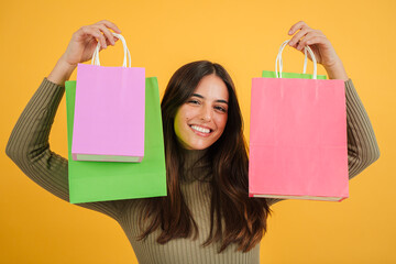Cheerful happy young adult caucasian woman enjoying and carrying shopping bags over yellow or...
