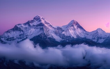 Majestic snow-capped mountains shrouded in soft clouds at dawn.