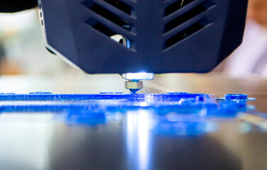 3D printer working close-up. 3D printer prints a model from molten yellow plastic close-up. 3D printer printing object. New modern prototyping technologies. Additive progressive high-tech technology.