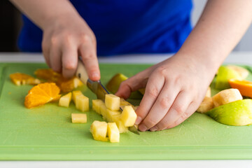 Girl's hands cutting fruit for salad. Selected Focus