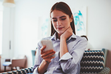 Young carefree caucasian woman checking banking balance via application on telephone, gorgeous...