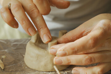A woman makes a clay product with her hands - a ceramic pot.