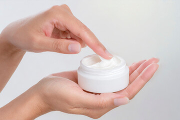 Woman's hands holding a jar of moisturizing cream on white background