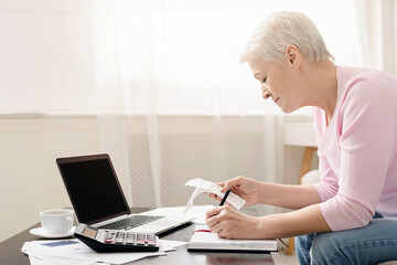 Senior woman accountant counting taxes and income at home, empty space