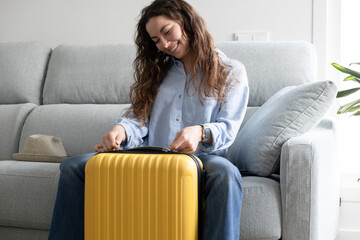 happy woman closes travel suitcase at home