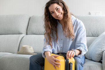 happy woman closes travel suitcase at home
