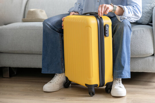 happy woman closes travel suitcase at home
