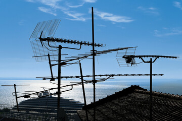 Silhouette of UHF antenna on roofs. The sea in the background.