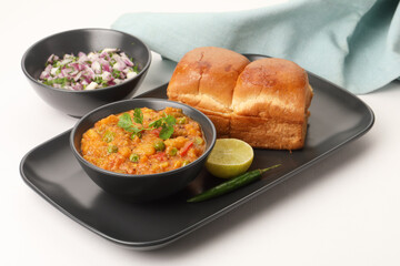 Pav Bhaji is a fast food dish from India, Thick and spicy vegetable curry, fried and served with a soft bread roll/Bun Pav and butter