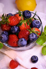 Fresh strawberries and blueberries in a glass bowl.