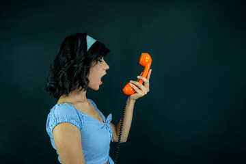 Young Woman Talking on Orange Retro Phone. Vintage Girl Talking Pin Up Phone. woman shouting while...