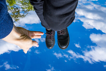Hanging feet with mountain boots, sky in background, beautiful nature scenario