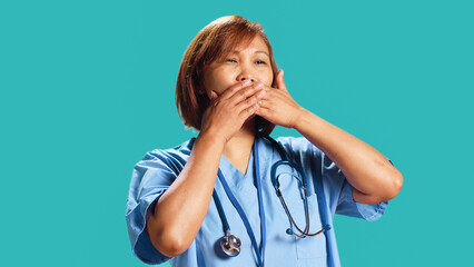 Certified nurse covering mouth with hands, holding back from saying rude thoughts. Hospital...