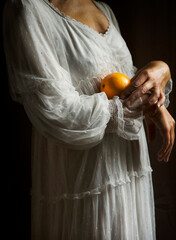 woman in white romantic style dress holding an orange in her arms II