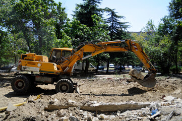 A large excavator flattens and breaks the remains of the building it demolished.