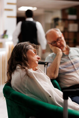 Detailed shot of retired senior woman and man, each sleeping on cozy couch while waiting to...