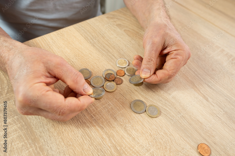 Wall mural senior man, poor pensioner lays out euro cent coins on wooden table, counts meager cash money on tab