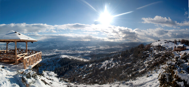 Panoramic view from  mountain Vodno. Winter photo with snow. The sun breaks through the clouds. A wooden house for tourists and hikers.