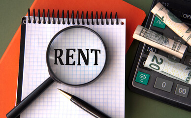 RENT - word under magnifying glass on the background of calculator and banknotes