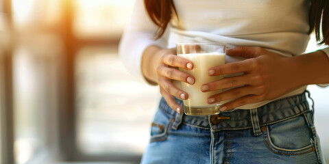 Female hands hold a glass of milk. Lactose intolerance, cow protein, alternative plant milk concept.