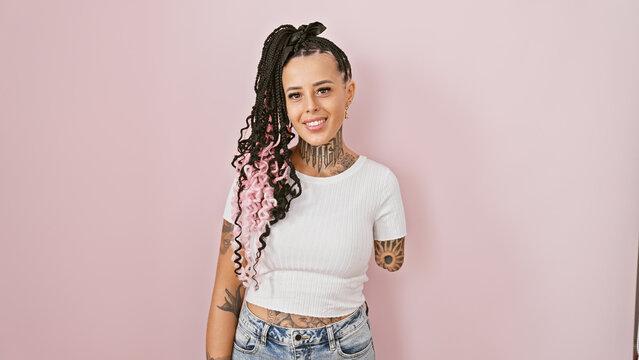 Cheerful hispanic amputee woman, radiating confidence and joy, standing tall over a pink isolated background, smiles contagiously