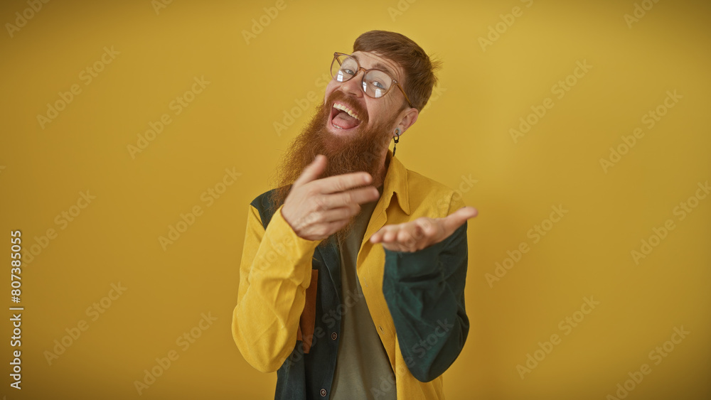 Wall mural Bearded young man in glasses laughing joyously against a yellow background