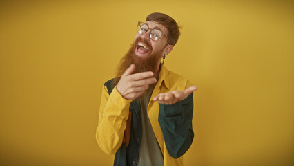 Bearded young man in glasses laughing joyously against a yellow background