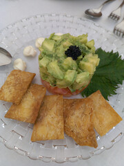 Avocado timbale with salmon decorated on a glass plate.  