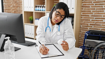 A female doctor in a clinic writes a prescription while examining medication against an indoor...