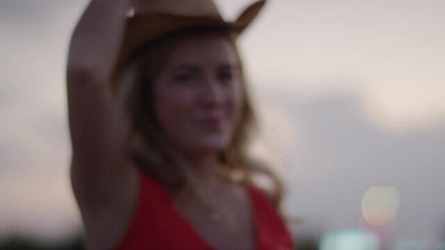 Woman grabs a cowboy hat from the back of a truck and puts it on at a country concert tailgate
