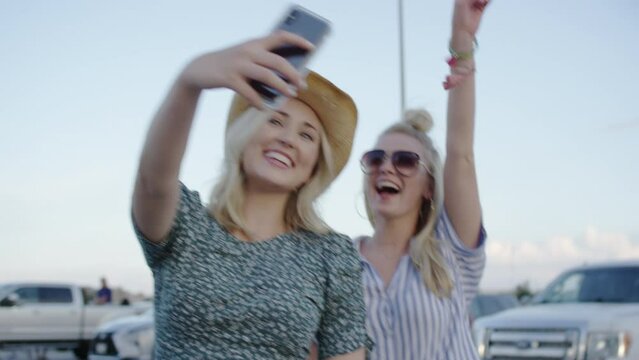 Two college students take a selfie in a parking lot at a country concert