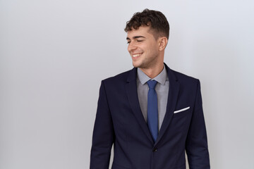 Young hispanic business man wearing suit and tie looking away to side with smile on face, natural...