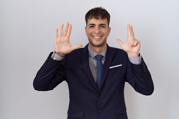 Young hispanic business man wearing suit and tie showing and pointing up with fingers number eight while smiling confident and happy.