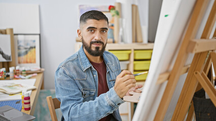 A bearded man painting on a canvas in an art class, depicting creativity and education in a casual...